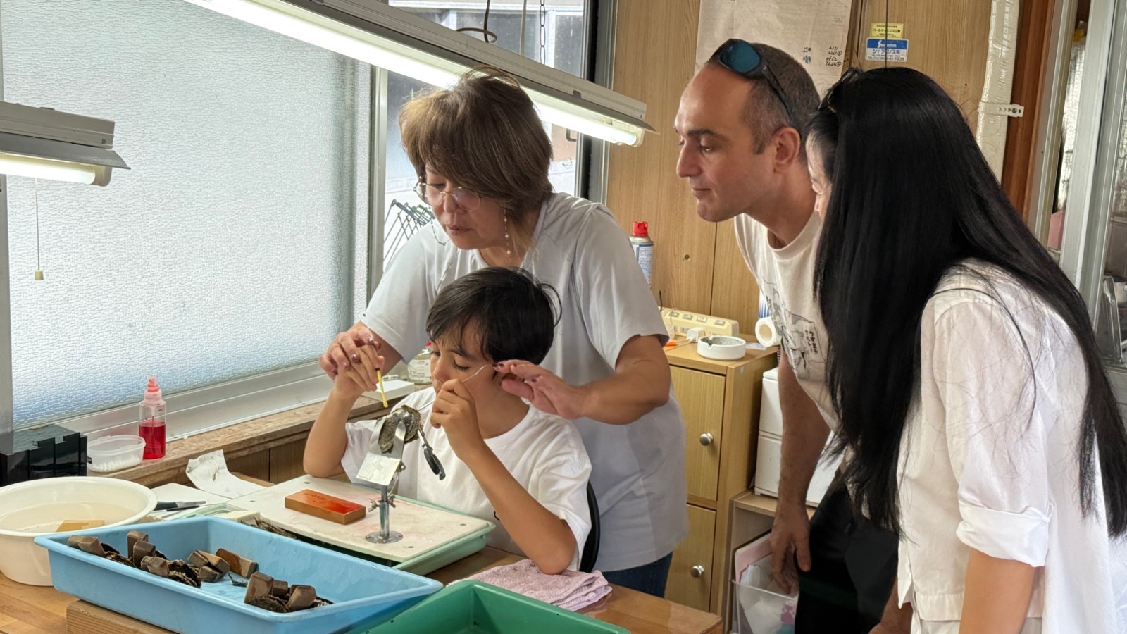 Guests at the workbench of a working akoya pearl farm in Ise-Shima, learning to place a nucleus into a pearl oyster with the farmer
