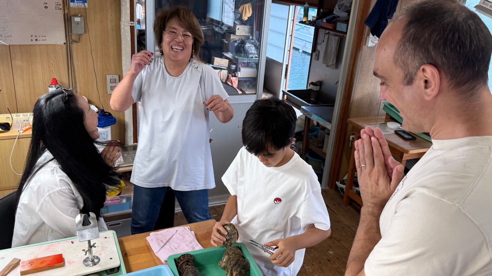 Guests and the pearl farmer laughing together after opening the shells at a family-run akoya pearl farm in Ise-Shima